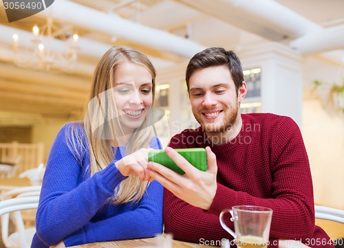 Image of smiling couple with smartphone drinking tea
