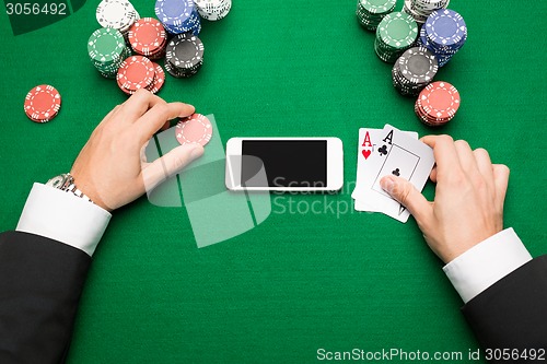 Image of casino player with cards, smartphone and chips