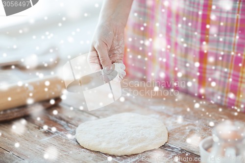 Image of close up of woman hand sprinkling dough with flour