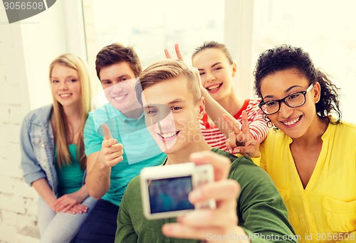 Image of five smiling students taking picture with camera