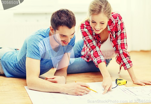 Image of smiling couple looking at blueprint at home