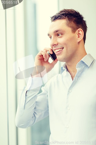 Image of smiling businessman with smartphone in office