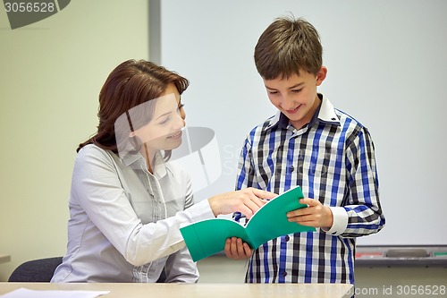 Image of school boy with notebook and teacher in classroom