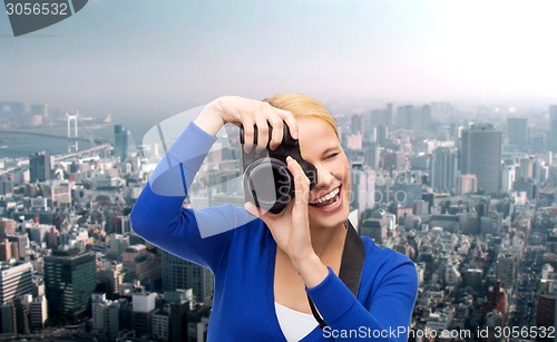 Image of smiling woman taking picture with digital camera