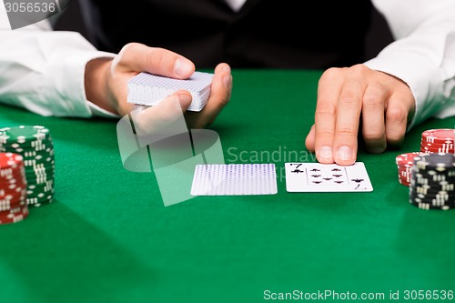 Image of holdem dealer with playing cards and casino chips