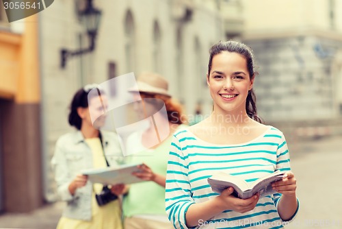 Image of smiling teenage girls with city guides and camera