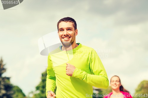 Image of smiling couple running outdoors