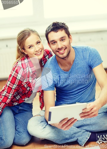 Image of smiling couple looking at tablet pc at home