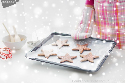 Image of close up of woman with cookies on oven tray