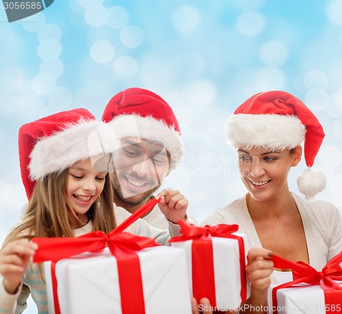 Image of happy family in santa hats sitting with gift boxes