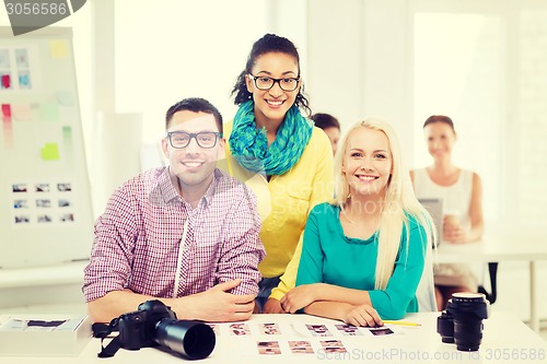 Image of smiling team with printed photos working in office