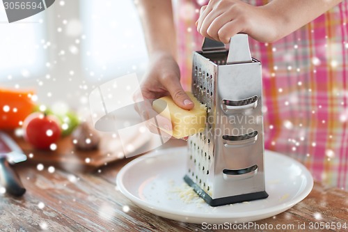 Image of close up of woman hands with grater grating cheese