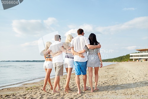 Image of smiling friends hugging and walking on beach