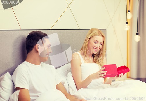 Image of smiling couple in bed with red gift box