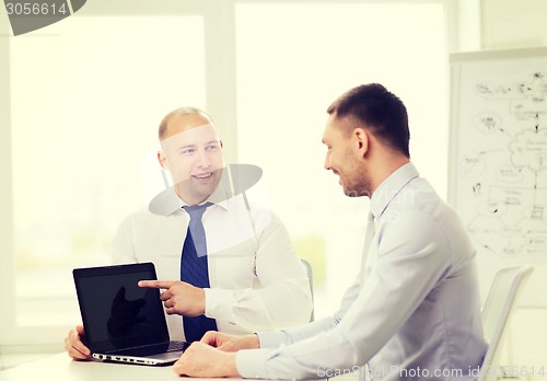 Image of two smiling businessmen with laptop in office