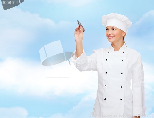 Image of smiling female chef writing something on air