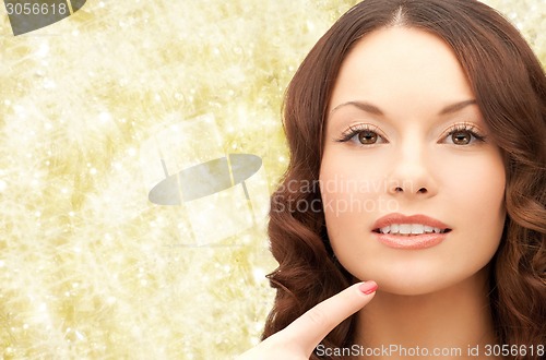 Image of beautiful young woman pointing finger to her chin