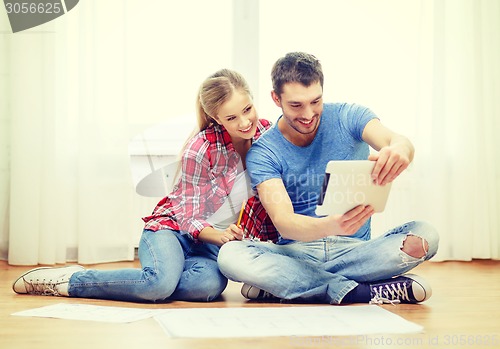 Image of smiling couple looking at tablet pc at home