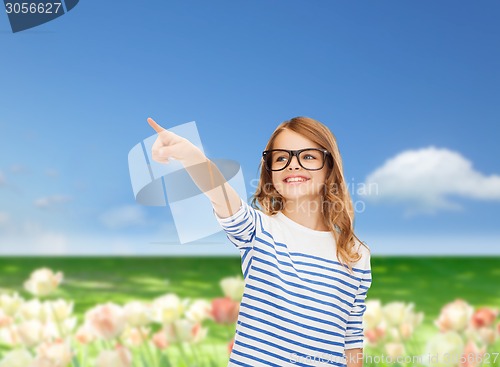 Image of cute little girl in eyeglasses pointing in the air