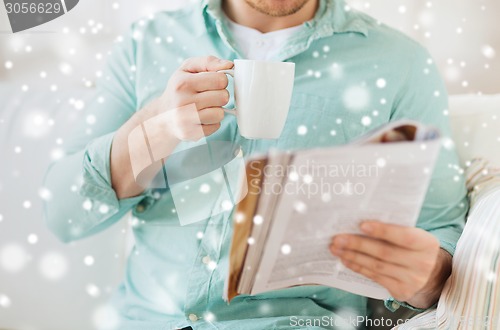 Image of close up of man with magazine drinking from cup