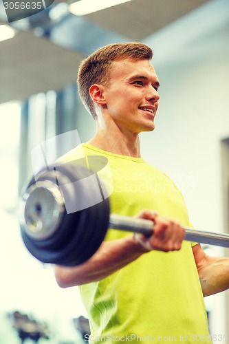 Image of smiling man doing exercise with barbell in gym