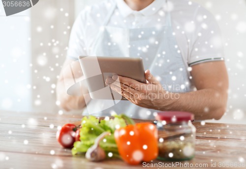 Image of closeup of man reading recipe from tablet pc