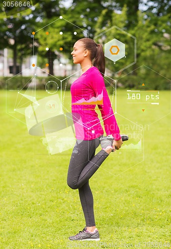 Image of smiling woman stretching leg outdoors