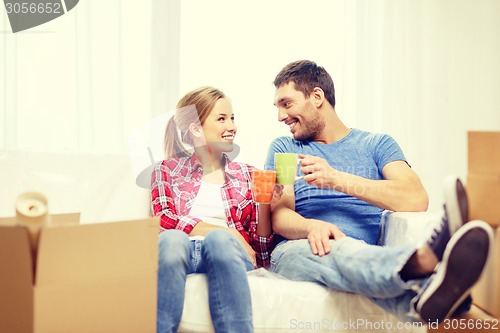 Image of smiling couple relaxing on sofa in new home