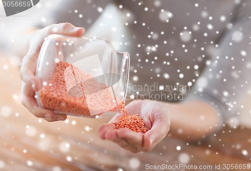 Image of close up of woman emptying jar with red lentils