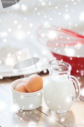 Image of close up of milk jug, eggs, whisk and flour