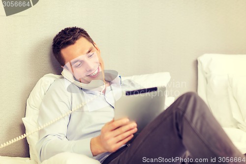 Image of businessman with tablet pc and phone in hotel room