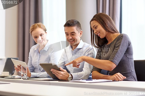 Image of smiling business people with tablet pc in office