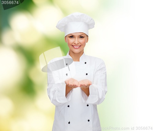 Image of smiling female chef holding something on hands