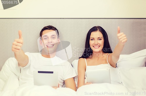 Image of smiling couple in bed with tablet pc computers