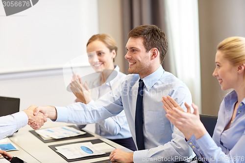 Image of smiling business team shaking hands in office