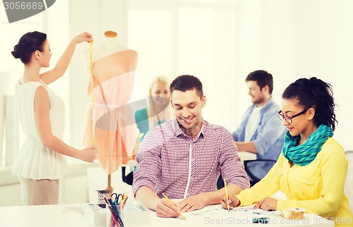 Image of smiling fashion designers working in office