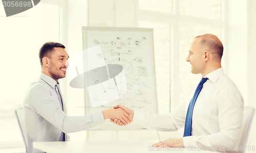 Image of two smiling businessmen shaking hands in office