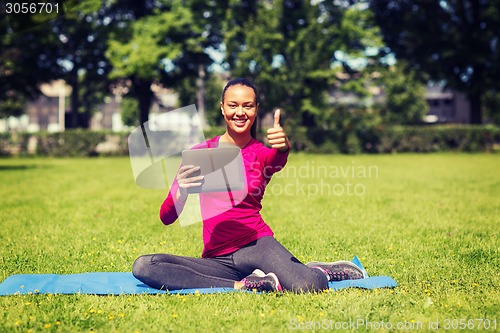 Image of smiling woman with tablet pc showing thumbs up