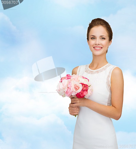 Image of smiling woman in white dress with bouquet of roses
