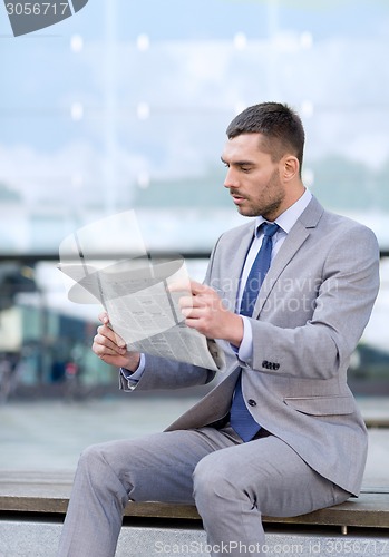 Image of young serious businessman newspaper outdoors