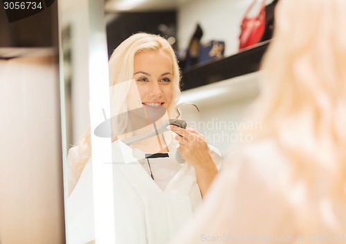 Image of happy young woman choosing clothes in mall