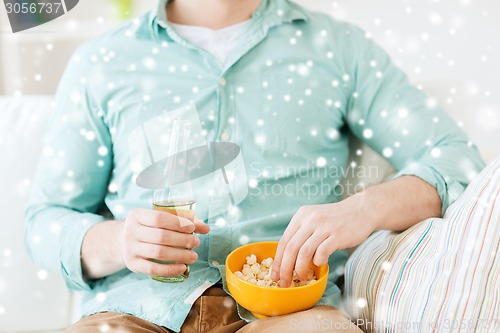 Image of close up of man with popcorn and beer at home