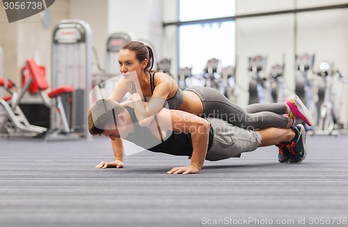 Image of smiling couple doing push-ups in the gym