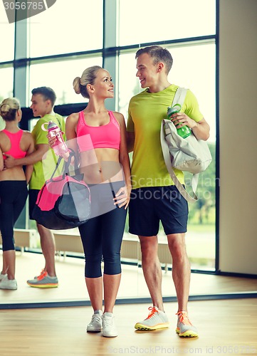 Image of smiling couple with water bottles in gym