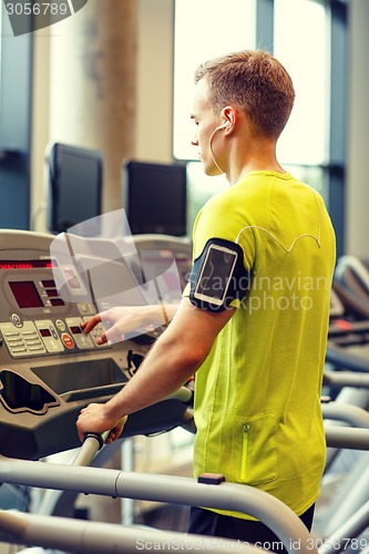 Image of man with smartphone exercising on treadmill in gym