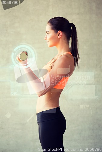 Image of smiling woman with dumbbells in gym