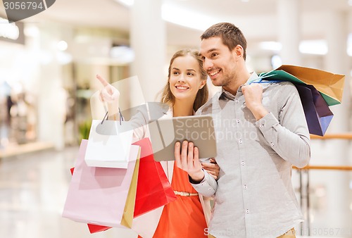 Image of couple with tablet pc and shopping bags in mall