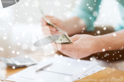 Image of close up of man counting money and making notes