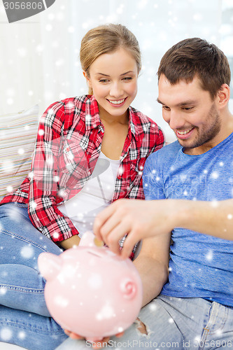 Image of smiling couple with piggybank sitting on sofa