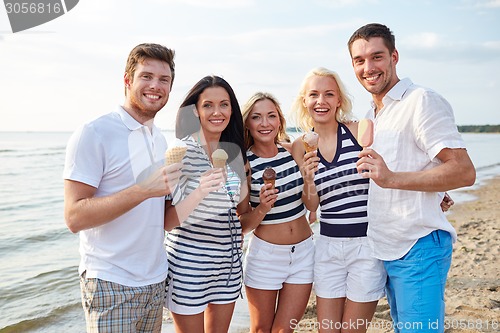 Image of smiling friends eating ice cream on beach